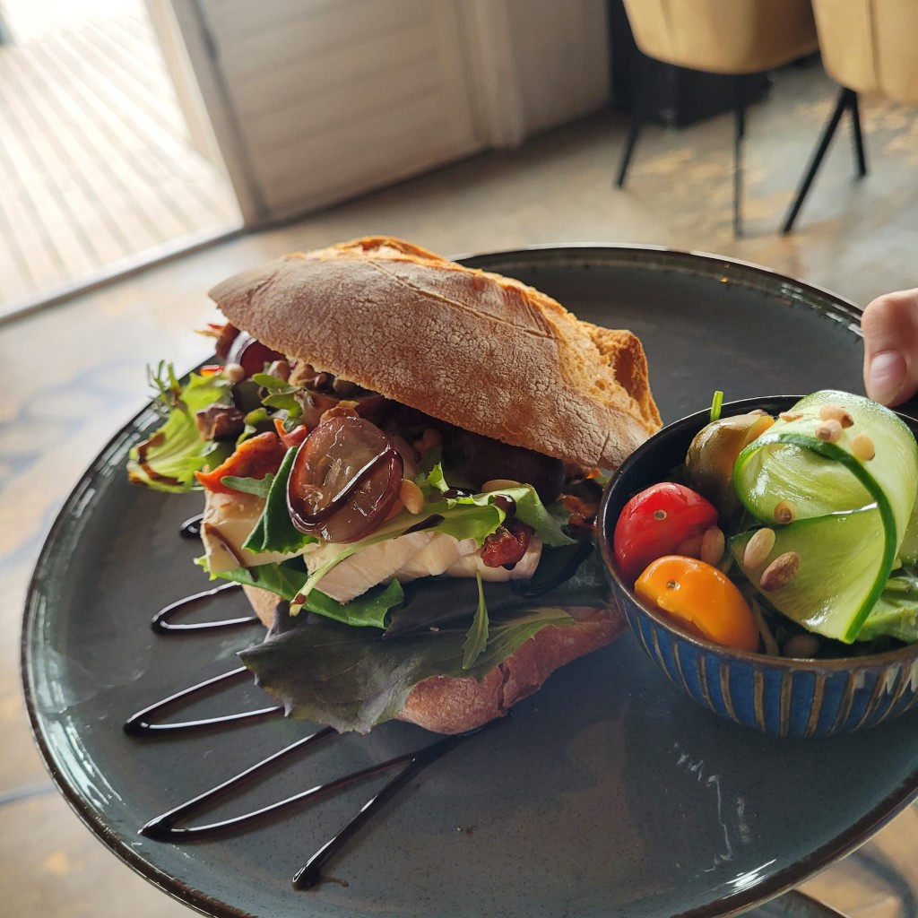 Broodje met brie, druiven en rucola op een bord