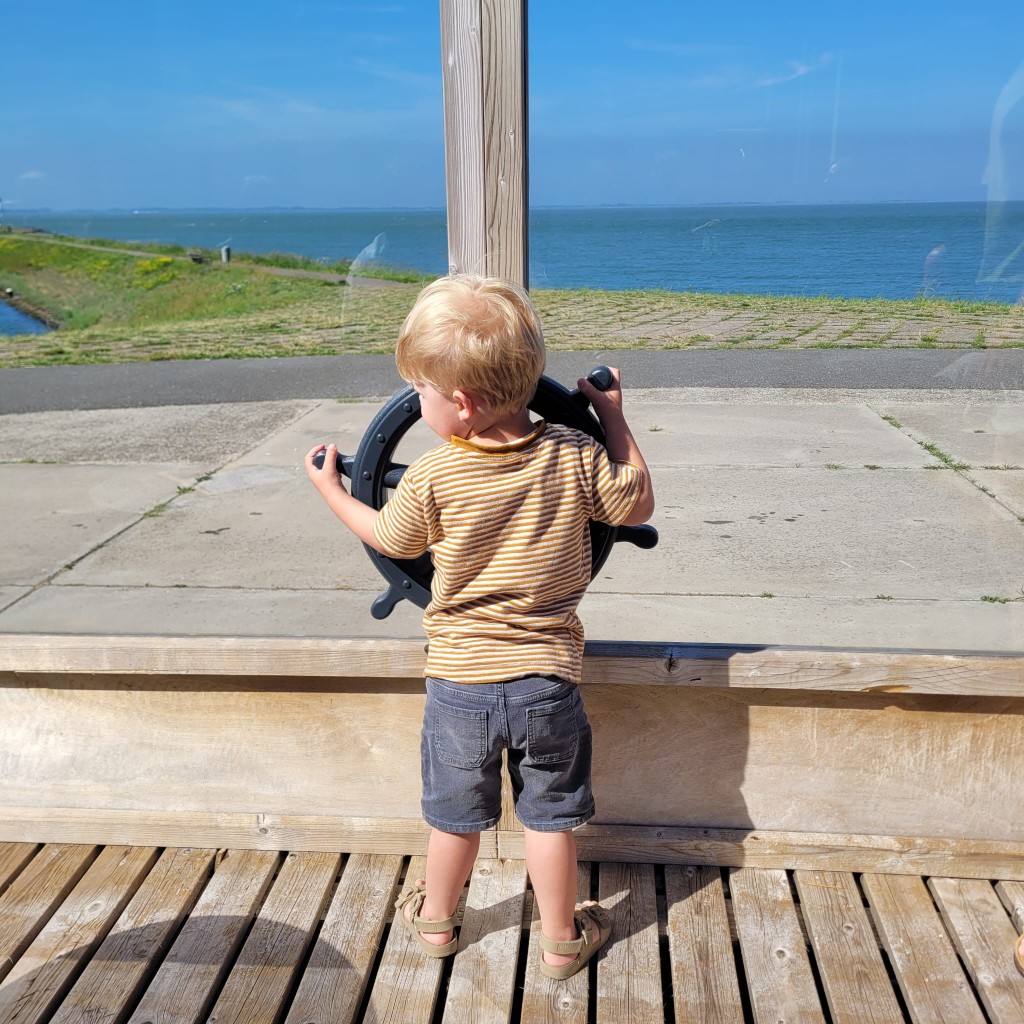 Kind aan het stuurwiel op het terras met uitzicht over het water